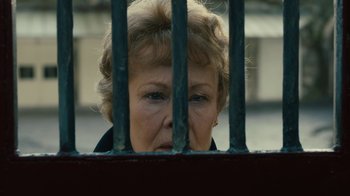 Movie still from “Philomena” (2013), directed by Stephen Frears – An older woman peering through the bars of a gate; Close Up shot, Low angle