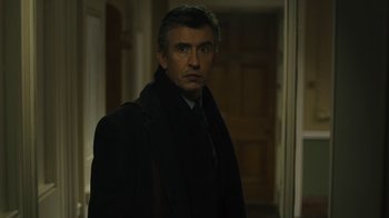 Movie still from “Philomena” (2013), directed by Stephen Frears – A man wearing a coat and tie standing in front of a door; Close Up shot, Low angle