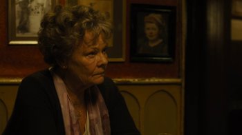 Movie still from “Philomena” (2013), directed by Stephen Frears – An older woman sitting at a table in front of a painting; Close Up shot, Over the shoulder angle