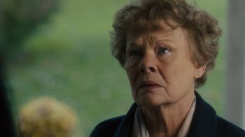 Movie still from “Philomena” (2013), directed by Stephen Frears – An older woman looking at the camera while wearing a jacket; Close Up shot, Over the shoulder angle