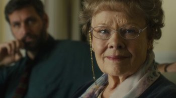 Movie still from “Philomena” (2013), directed by Stephen Frears – An older woman wearing glasses and a necklace; Close Up shot, Over the shoulder angle
