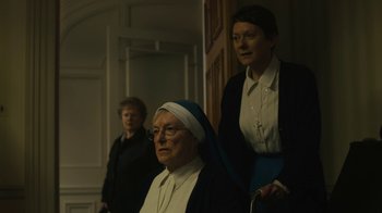 Movie still from “Philomena” (2013), directed by Stephen Frears – Two women and a man are standing in front of a door; Medium shot, Low angle