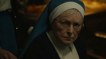 Movie still from “Philomena” (2013), directed by Stephen Frears – An older woman wearing a nun's outfit and wearing glasses; Close Up shot, Over the shoulder angle