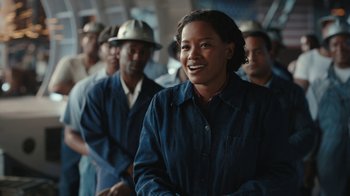 Movie still from “A League of Their Own” (2022), created by Abbi Jacobson – A woman standing in front of a group of people; Medium shot, Over the shoulder angle