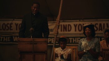 Movie still from “A League of Their Own” (2022), created by Abbi Jacobson – A man is giving a speech to a group of people; Medium shot, Over the shoulder angle