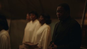 Movie still from “A League of Their Own” (2022), created by Abbi Jacobson – A group of people standing next to each other in a room; Medium shot, Over the shoulder angle