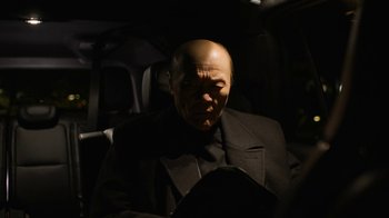 Movie still from “Full Circle” (2023), directed by Steven Soderbergh – A man with a bald head sitting in the back of a car; Close Up shot, Low angle