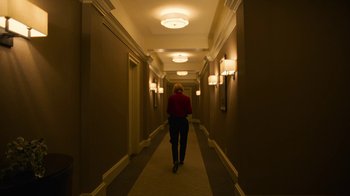 Movie still from “Full Circle” (2023), directed by Steven Soderbergh – A person walking down a long hallway in a building; Wide shot, High angle