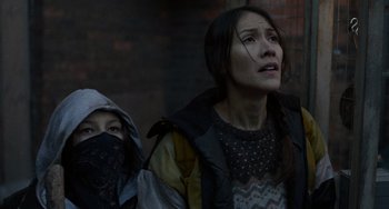 Two people standing next to each other near a brick wall