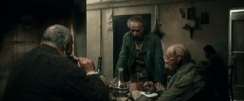 Movie still from “Pinocchio” (2019), directed by Matteo Garrone – A group of people sitting around a table; Medium shot, Over the shoulder angle