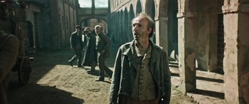 Movie still from “Pinocchio” (2019), directed by Matteo Garrone – A group of men walking on a dirt road; Medium shot, Over the shoulder angle