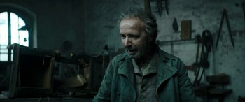 Movie still from “Pinocchio” (2019), directed by Matteo Garrone – An older man in a green jacket looking at the camera; Close Up shot, Over the shoulder angle
