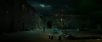 Movie still from “Pinocchio” (2019), directed by Matteo Garrone – A person standing in a courtyard under a cloudy sky; Extreme Wide shot, Low angle