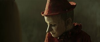 Movie still from “Pinocchio” (2019), directed by Matteo Garrone – A person wearing a red hat and a red dress; Extreme Close Up shot, Low angle