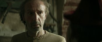 Movie still from “Pinocchio” (2019), directed by Matteo Garrone – An older man with a beard and mustache looking at the camera; Close Up shot, Over the shoulder angle