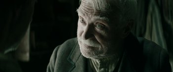 Movie still from “Pinocchio” (2019), directed by Matteo Garrone – An old man with white hair and blue eyes looking at the camera; Close Up shot, Over the shoulder angle