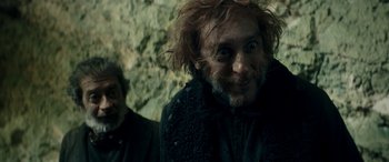 Movie still from “Pinocchio” (2019), directed by Matteo Garrone – A man with long hair and a beard is smiling for the camera; Close Up shot, Low angle