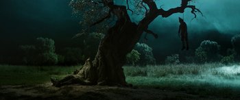 Movie still from “Pinocchio” (2019), directed by Matteo Garrone – A tree in the middle of a field with dark sky in the background; Extreme Wide shot, High angle