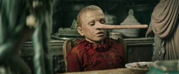 Movie still from “Pinocchio” (2019), directed by Matteo Garrone – A wooden doll with a long nose being held by a wooden stick; Extreme Close Up shot, Over the shoulder angle