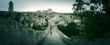 Movie still from “Pinocchio” (2019), directed by Matteo Garrone – A person is walking down a stone walkway; Extreme Wide shot, Low angle