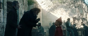 Movie still from “Pinocchio” (2019), directed by Matteo Garrone – Two people in costumes are talking to each other outside; Medium shot, Low angle