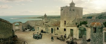 Movie still from “Pinocchio” (2019), directed by Matteo Garrone – A group of people sitting around a building; Extreme Wide shot, High angle