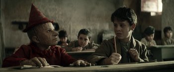 Movie still from “Pinocchio” (2019), directed by Matteo Garrone – A group of children sitting at a table with a pencil; Close Up shot, Over the shoulder angle