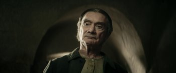 Movie still from “Pinocchio” (2019), directed by Matteo Garrone – An old man with a beard is looking at the camera; Close Up shot, Low angle