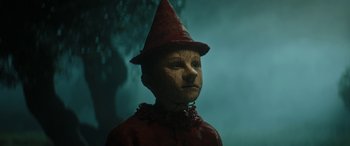 Movie still from “Pinocchio” (2019), directed by Matteo Garrone – A creepy doll wearing a red outfit and a red hat; Close Up shot, Low angle