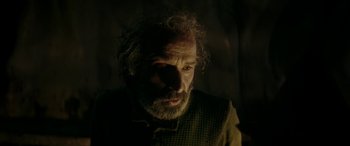 Movie still from “Pinocchio” (2019), directed by Matteo Garrone – A man with long hair and a beard is looking at the camera; Close Up shot, Over the shoulder angle