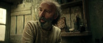 Movie still from “Pinocchio” (2019), directed by Matteo Garrone – An old man with a beard is sitting in a room; Close Up shot, Low angle