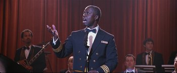 Movie still from “Poseidon” (2006), directed by Wolfgang Petersen – A man in a suit and tie speaking into a microphone; Close Up shot, Low angle