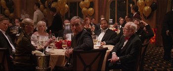 Movie still from “Poseidon” (2006), directed by Wolfgang Petersen – A group of people sitting around a table with wine glasses; Medium shot, Over the shoulder angle