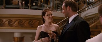 Movie still from “Poseidon” (2006), directed by Wolfgang Petersen – A man and a woman are holding a glass of champagne; Medium shot, Over the shoulder angle