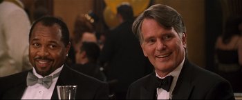 Movie still from “Poseidon” (2006), directed by Wolfgang Petersen – A person wearing a suit and tie; Close Up shot, Over the shoulder angle