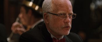 Movie still from “Poseidon” (2006), directed by Wolfgang Petersen – An older man wearing glasses and a red bow tie; Close Up shot, Over the shoulder angle