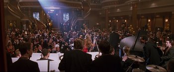 Movie still from “Poseidon” (2006), directed by Wolfgang Petersen – A crowd of people sitting in a large room; Extreme Wide shot, High angle