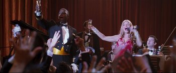 Movie still from “Poseidon” (2006), directed by Wolfgang Petersen – A group of people standing in front of a crowd holding wine glasses and toasting; Medium shot, Low angle