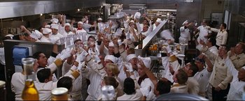 Movie still from “Poseidon” (2006), directed by Wolfgang Petersen – A group of people in a kitchen raising their glasses in the air; Wide shot, High angle