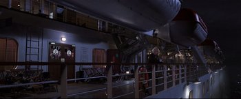 Movie still from “Poseidon” (2006), directed by Wolfgang Petersen – A man standing next to a railing on a train; Wide shot, High angle