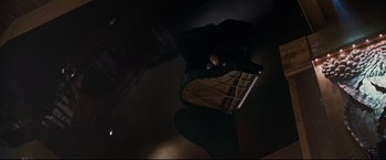 Movie still from “Poseidon” (2006), directed by Wolfgang Petersen – A person is playing the piano in a dark room; Wide shot, Overhead angle