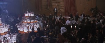Movie still from “Poseidon” (2006), directed by Wolfgang Petersen – A group of people sitting around a room with food; Extreme Wide shot, High angle
