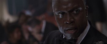Movie still from “Poseidon” (2006), directed by Wolfgang Petersen – An older man in a black shirt and black tie; Close Up shot, Low angle