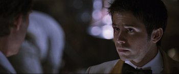 Movie still from “Poseidon” (2006), directed by Wolfgang Petersen – A person wearing a suit and tie; Close Up shot, Over the shoulder angle