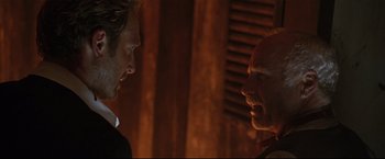 Movie still from “Poseidon” (2006), directed by Wolfgang Petersen – Two men talking to each other in front of a wooden wall; Close Up shot, Over the shoulder angle