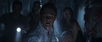 Movie still from “Poseidon” (2006), directed by Wolfgang Petersen – A group of people standing around a man in the dark; Close Up shot, Low angle
