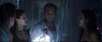 Movie still from “Poseidon” (2006), directed by Wolfgang Petersen – A man holding a flashlight while standing next to a waterfall; Close Up shot, Low angle