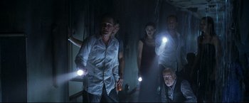 Movie still from “Poseidon” (2006), directed by Wolfgang Petersen – A group of people standing in a dark room holding lights; Medium shot, Low angle