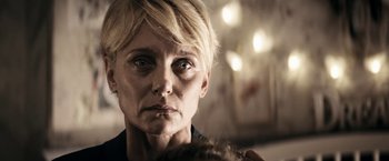 Movie still from “Prey for the Devil” (2022), directed by Daniel Stamm – An older woman with short blonde hair looking at the camera; Close Up shot, Over the shoulder angle