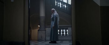 Movie still from “Prey for the Devil” (2022), directed by Daniel Stamm – A woman standing in front of a stair case; Wide shot, Low angle